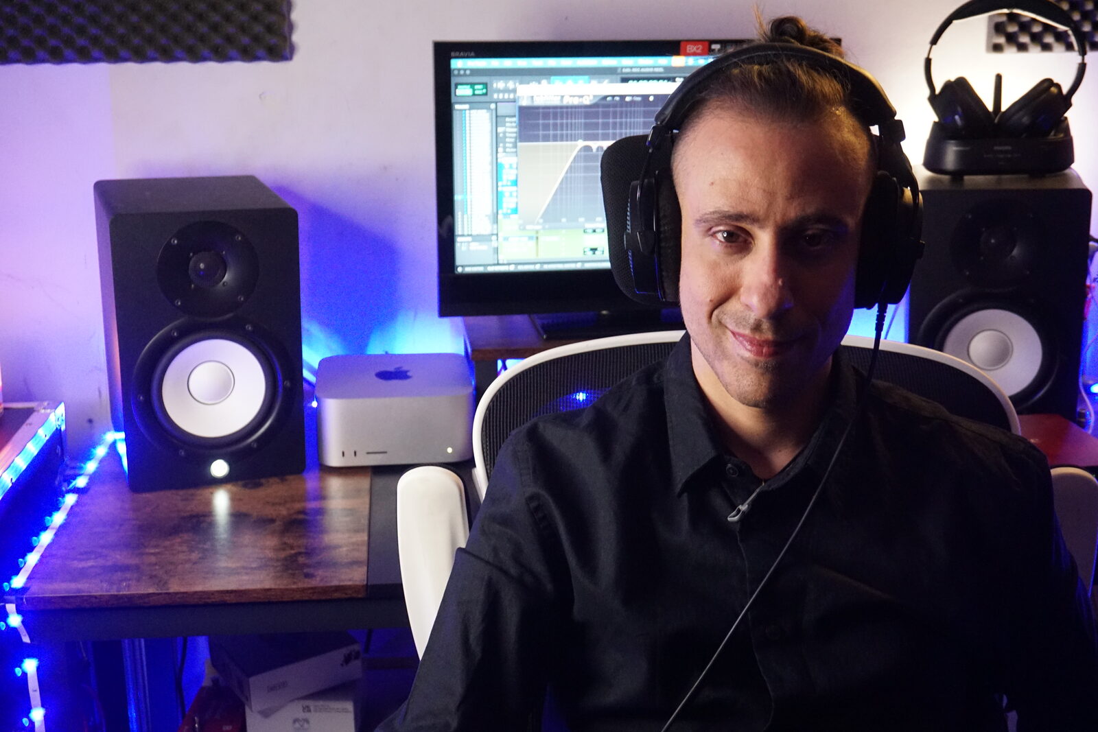 Alberto Aparicio sonriendo en su estudio, con los cascos y el monitor detrás